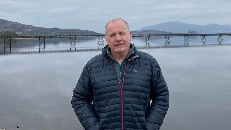 Elfed Powell Roberts o flaen y bont yn 2024