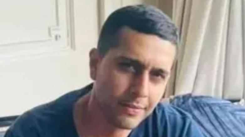 Kamran Rasool Aman, looking at the camera. His head is slightly tilted to one side, and he wears a blue t-shirt and has short black hair.