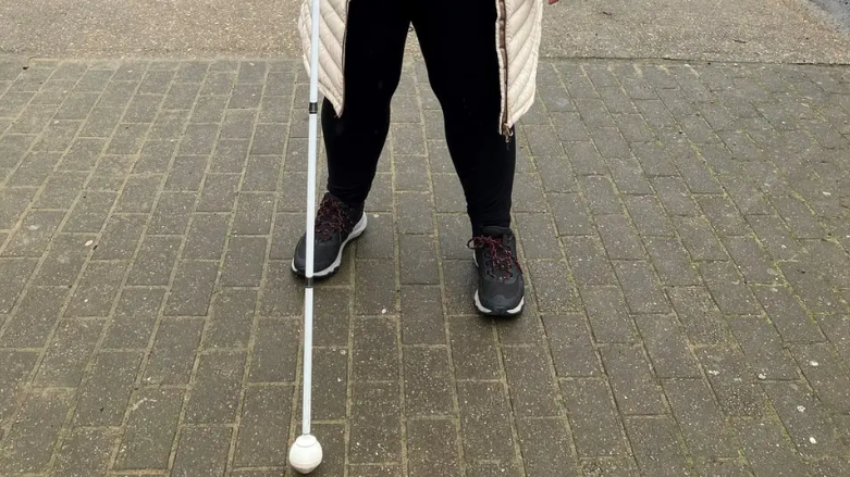 White cane with a ball on the end in front a person