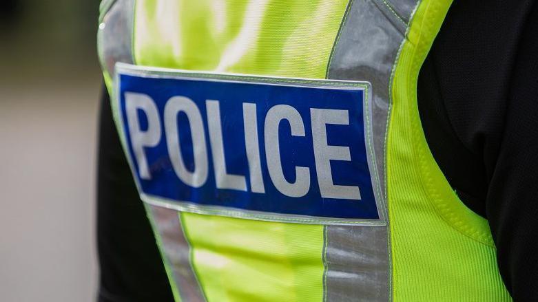 A police officer wearing a hi-vis jacket that says the words "Police" on the back