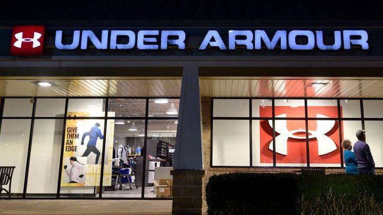 Building with Under Armour sign lit up, and two people outside in the street