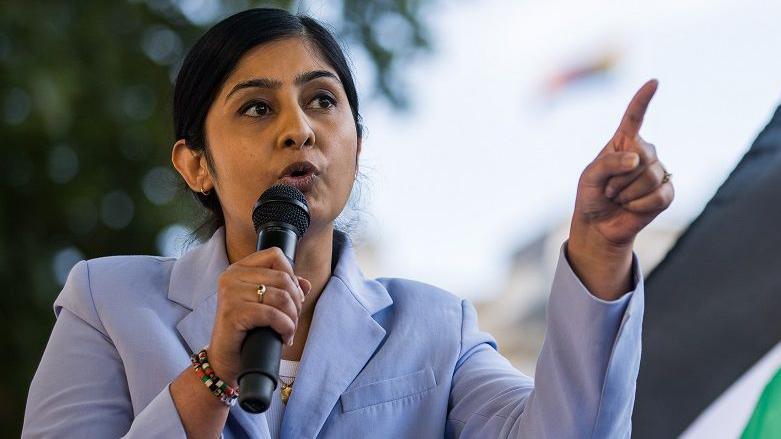 Zarah Sultana, a young woman holding a microphone, and dressed in a pale blue jacket, addresses pro-Palestinian activists at a Defend The Right to Protest rally