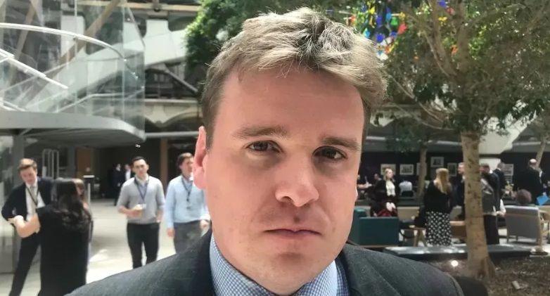 Tom Hunt standing in Portcullis House in a suit and shirt