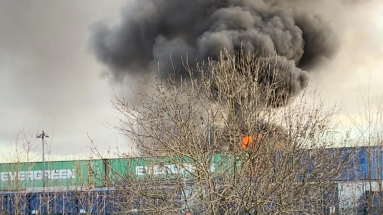 A large black cloud of smoke is coming from a fire in the industrial area