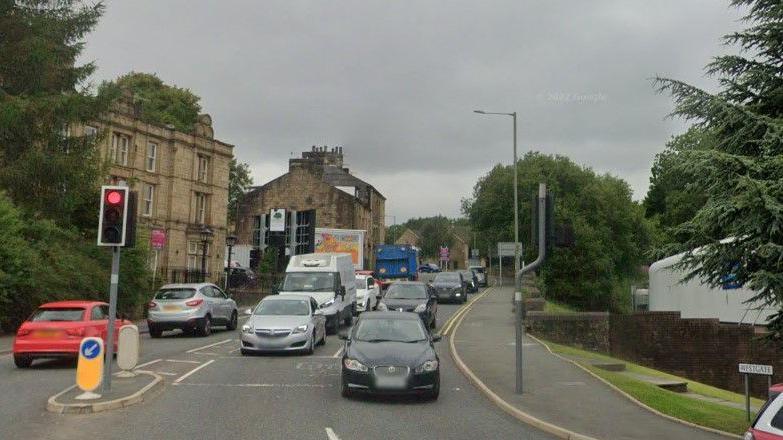 The start of Westgate in Burnley, with cars, a traffic light on red and a number of buildings in the background.