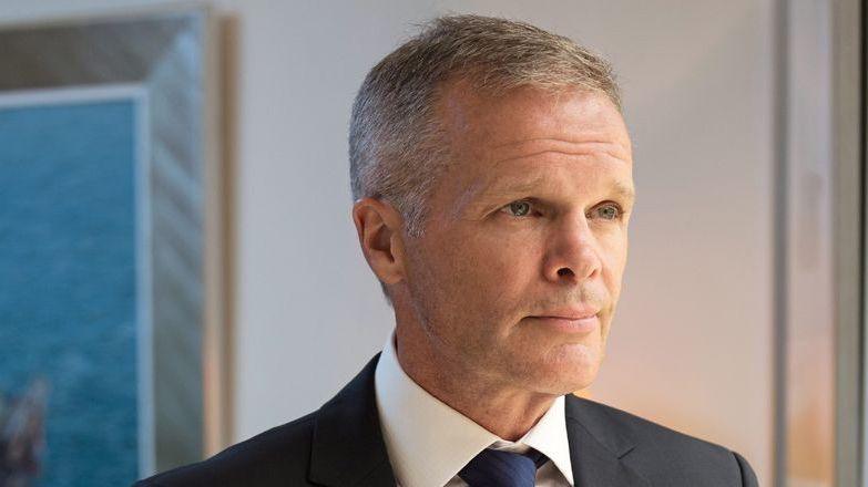A man with greying hair and a dark suit