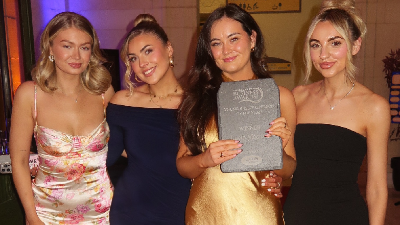 A picture of Lucie Macleod and three of her staff members at an awards ceremony. They are all looking at the camera. They are all wearing dresses and Lucie is holding an award. 