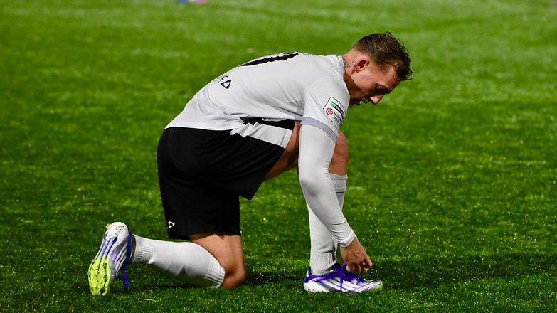 Ymosodwr Ricardo Rees sy'n gwisgo crys gwyn, siorts du, sanau gwyn a bŵts porffor yn ystod gem i GPC Merthyr.