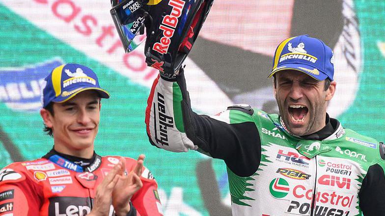 Marc Marquez applauds as Johann Zarco celebrates on the podium after winning MotoGP's 2025 French Grand Prix