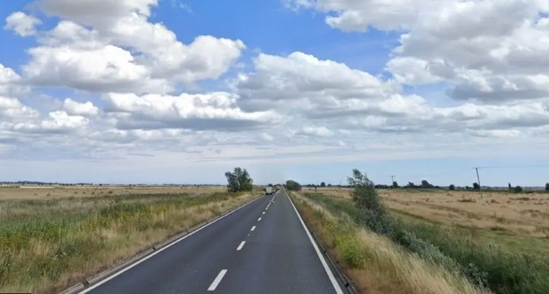 Acle Straight road showing broken white line down middle of road and fields either side 