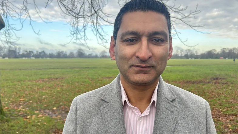 Afzal Shah looking into the camera wearing a grey jacket with the Bristol downs in the background