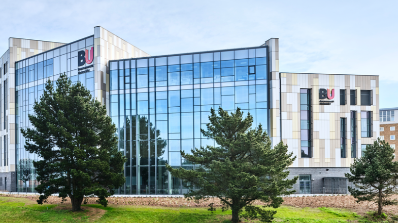 Bournemouth University glass building with two BU signs and three trees in front of the campus.