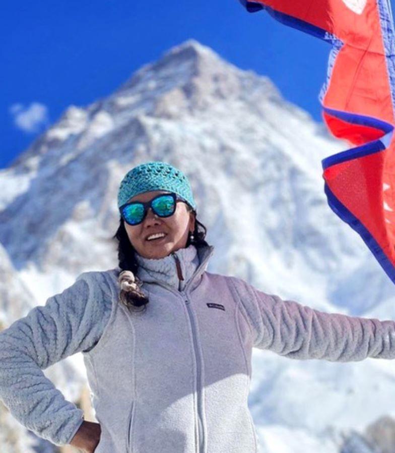 Lhakpa Sherpa smiling on a mountain with a flag