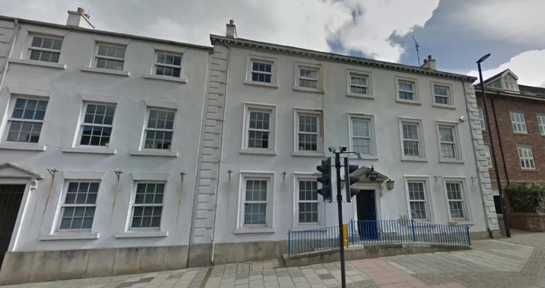 A row of Georgian buildings with several rows of windows. Two of the buildings are white - one on the far left is brick built. 