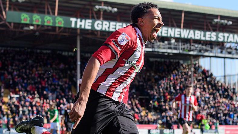 A smiling Lincoln City striker Alfie Lloyd wheels away after scoring against Stockport