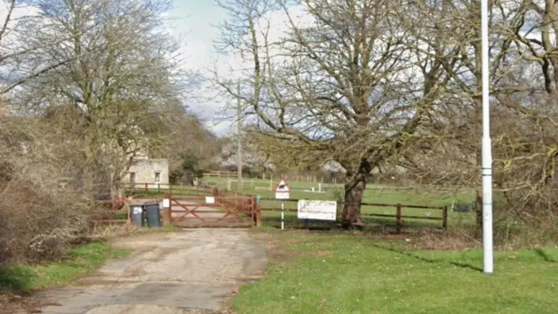 The Lynch Farm entrance, showing a field with a red wooden gate.