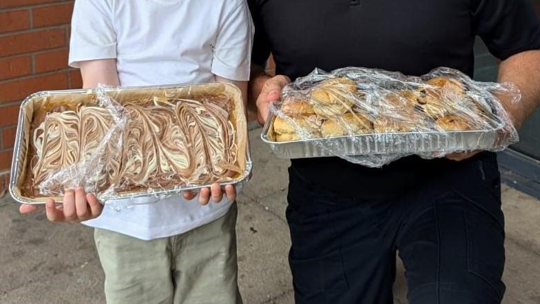 A little boy and a man, faces not shown, holding trays of millionaire cake and scones