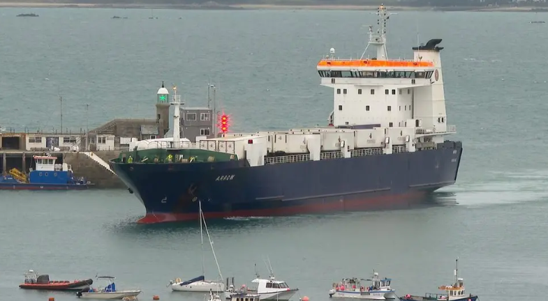 A blue ship, called MV Arrow, with a white cabin entering St Peter Port Harbour. 