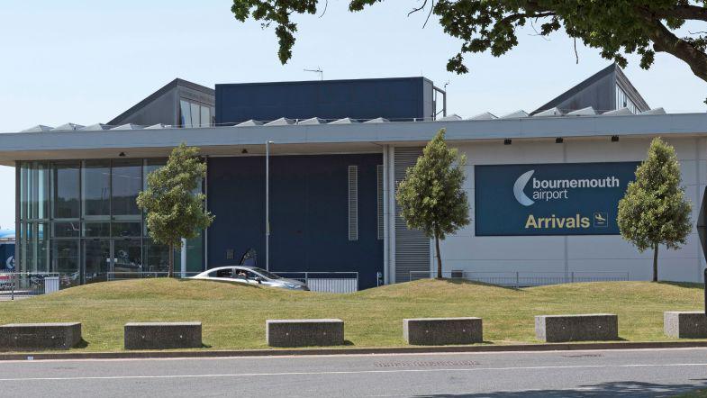 The outside of the Bournemouth Airport terminal building, which is grey with pillars.