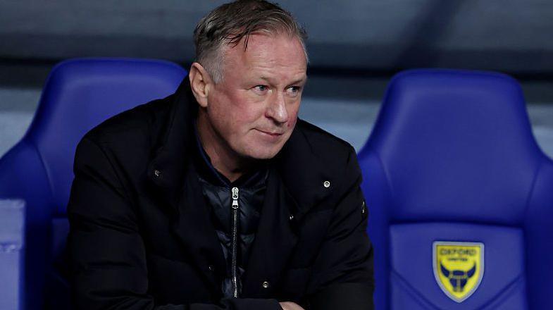 Blackburn Rovers boss Michael O'Neill sits in the Oxford United dugout at the Kassam Stadium