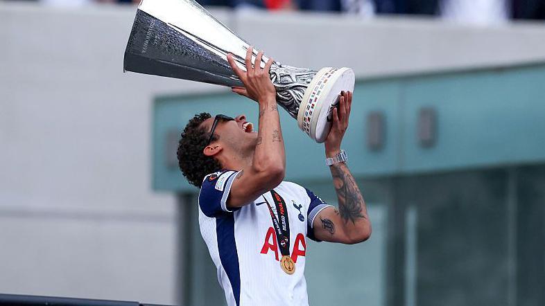 Brennan Johnson holds the Europa League trophy aloft at Tottenham Hotspur's victory parade in 2025