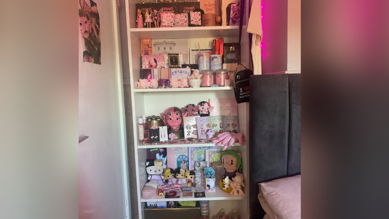 A bookcase full of Melanie Martinez merchandise including chunky Mary Jane style shoes and dolls with blonde and black hair