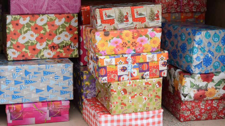 Christmas presents in shoe boxes wrapped up in colourful paper, all in different patterns.