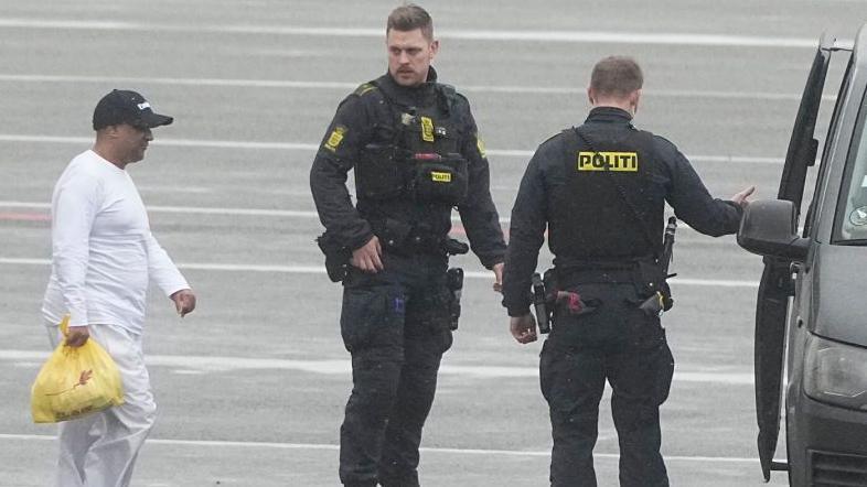 British businessman Sanjay Shah (L) is seen next to Danish police officers as he arrives at Kastrup Airport in Copenhagen on December 6, 2023.