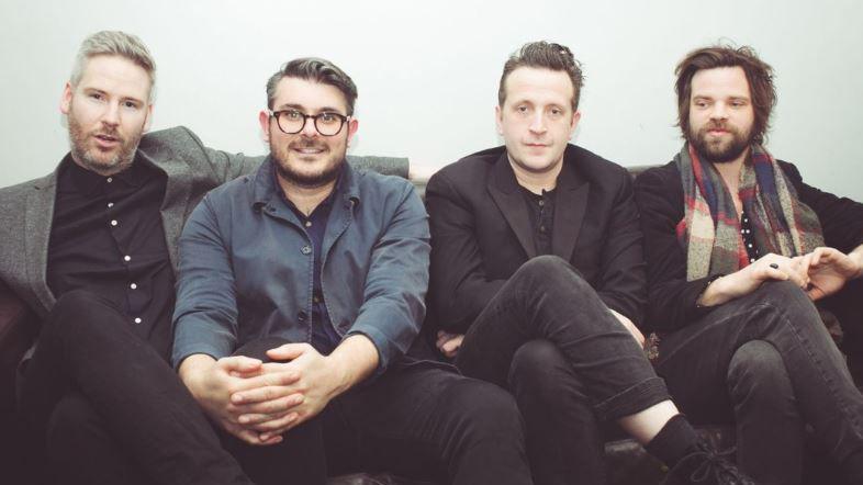 The Futureheads, band members Ross Millard (vocals and guitar), David "Jaff" Craig (vocals and bass guitar) and brothers Barry Hyde (vocals and guitar) and Dave Hyde (drums) sitting on a sofa.