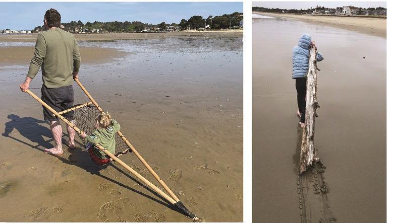 A man dragging a travois across the sand with a little girl inside and a person dragging a stick across the sand. 