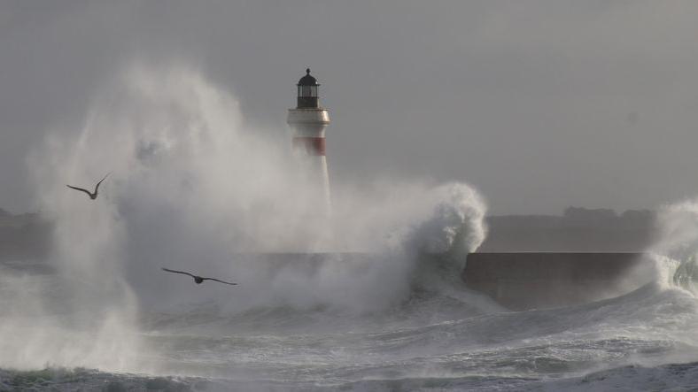 Big waves breaking against breakwater.