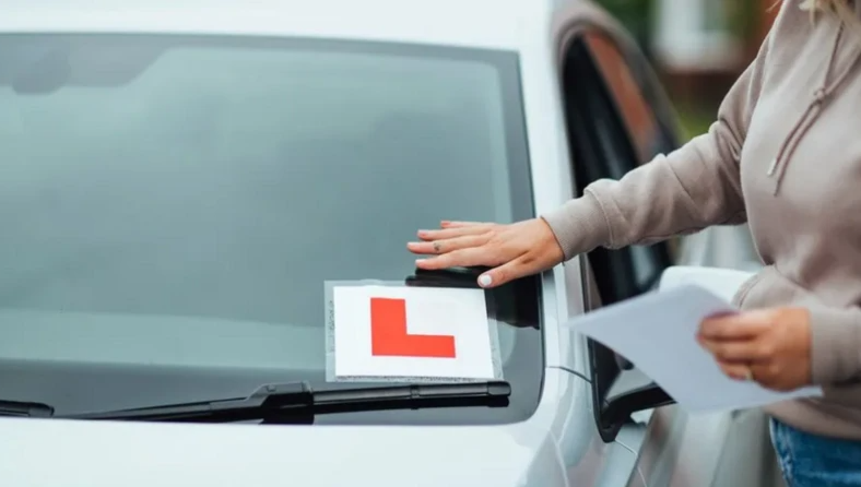 Person sticking an L plate on the windscreen of a car