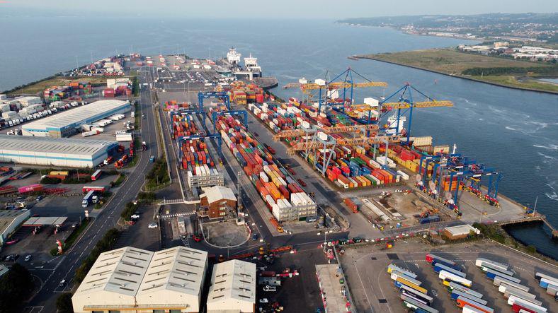 Belfast port, an aerial shot of a peninsula of land, surrounded by water with rows of shipping containers, cranes and warehouses.