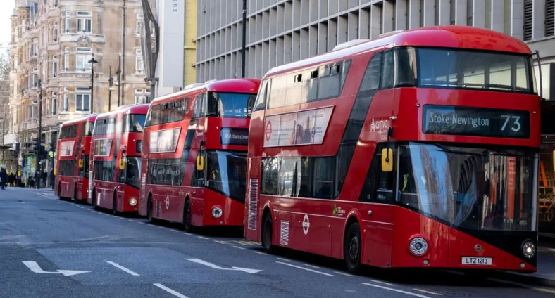 Four red London double-decker buses lined up on a road in the capital