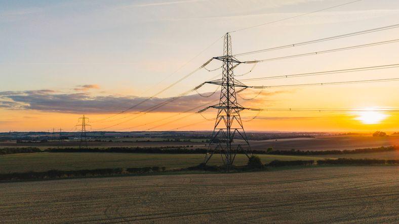 An elevated/drone view of an electricity pylon in the UK at sunset