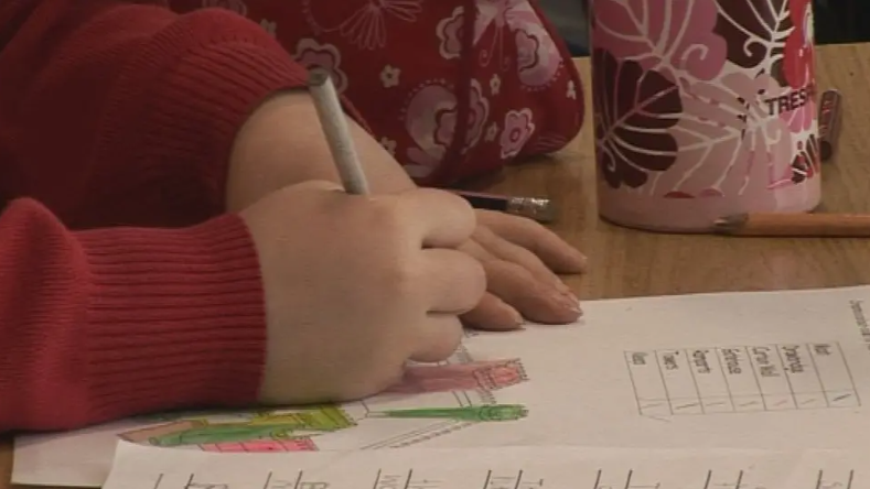 Pàiste a' sgrìobhadh le peann ann an seòmar-teagaisg bun-sgoile Gàidhlig