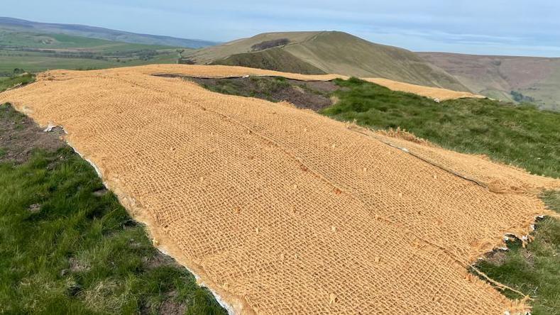 A hillside covered with beige hessian sheeting