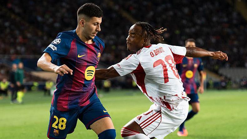 Roony Bardghji of FC Barcelona plays in front of Bruno Onyemaechi of Olympiacos
