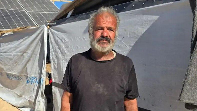 Khaled Halas, an elderly man wearing a black shirt, looks to his left.