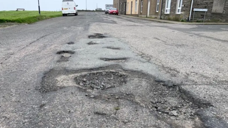 Dealbh a thogadh an 2024 de tholl san rathad an Gallaibh