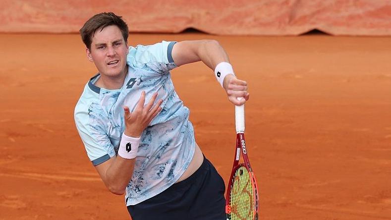 Henry Patten serves during a French Open men's doubles match