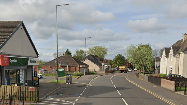 A Post Office and Morrisons shop on the left side of a road with houses opposite