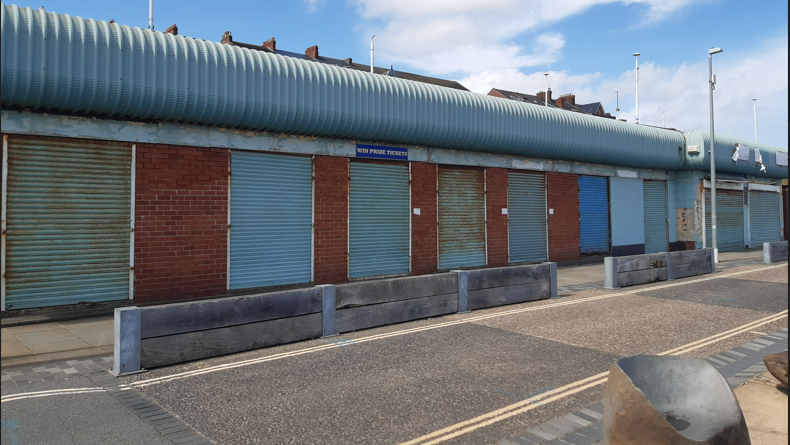 A single story row of buildings with shutters.