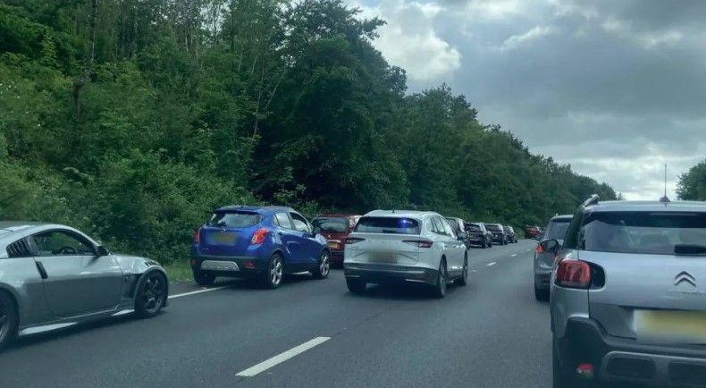 An unmarked police car with its blue lights on drives along the A38 in Devon to the scene of a crash. Both lanes of traffic have moved over to allow space for the vehicle to move through.