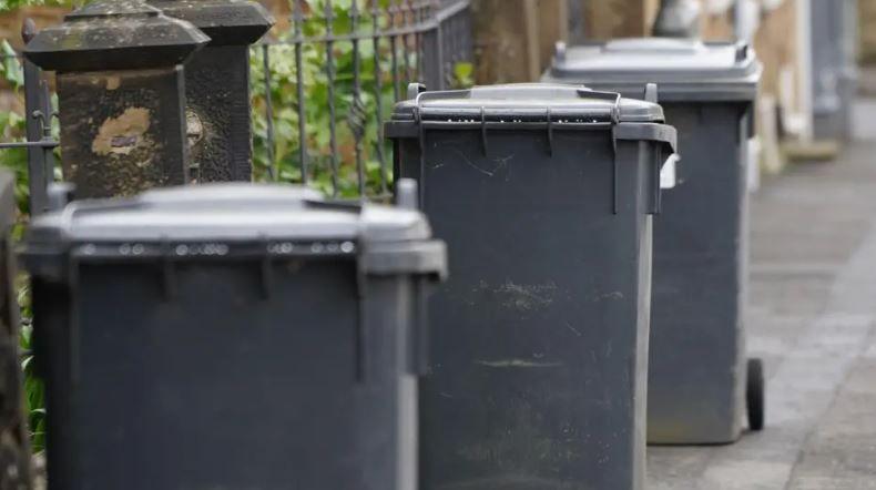 Three grey bins on a street in a row, with the bins put out ready for collection. 