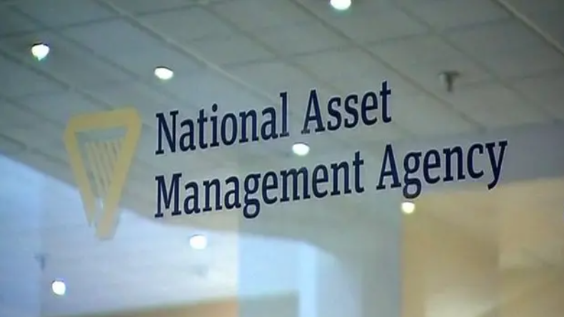 A glass wall with the words 'National Asset Management Agency' written in blue type beside a gold harp symbol.