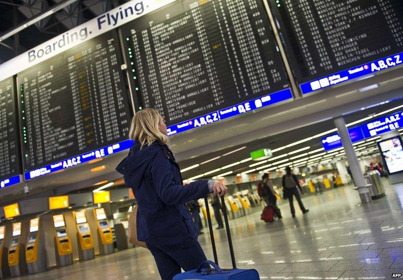 A passenger stands in front of an information board displaying flights at Frankfurt airport (12 March 2013)