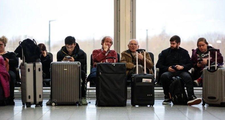 People sitting with their luggage waiting in an airport