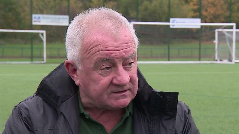 Steve Dale. He has short white hair and is sitting next to a football pitch.