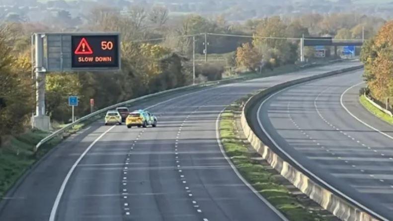 Two police cars are seen stopped on the motorway next to a car.